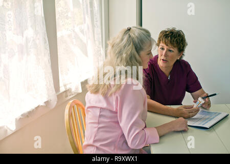 Nurse discussing medication with a senior patient. Stock Photo