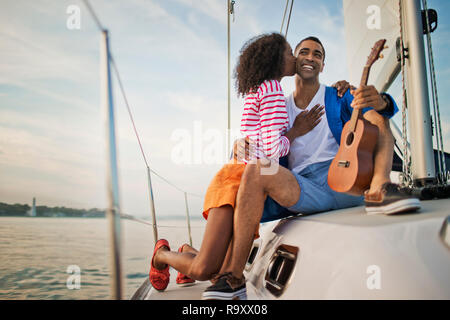 Happy young couple having fun playing the ukulele while sailing. Stock Photo