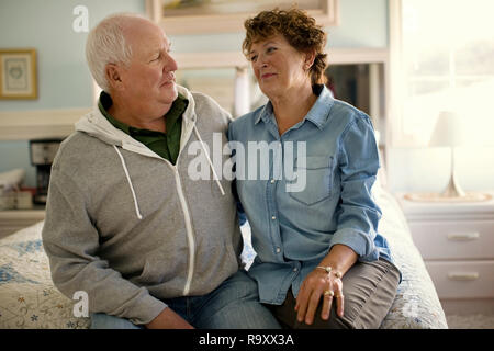 Affectionate mature couple enjoy spending time together sitting on the bed. Stock Photo