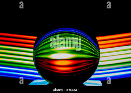 Light painting with a lens ball / crystal ball / glass ball / sphere with colorful blue striped reflections on black surface - Copy space Stock Photo