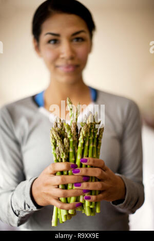 Portrait of a young woman holding a bunch of fresh asparagus. Stock Photo