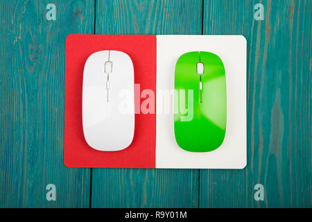 Green and white computer mouses, notepad on blue wooden background Stock Photo