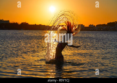 Girl Flipping Hair Flip At Sunset Beach In Orange Sky Stock Photo