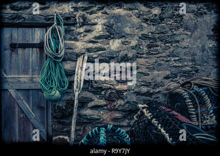 Old wall with lobster pots and rope in Hope Cove, Devon Stock Photo