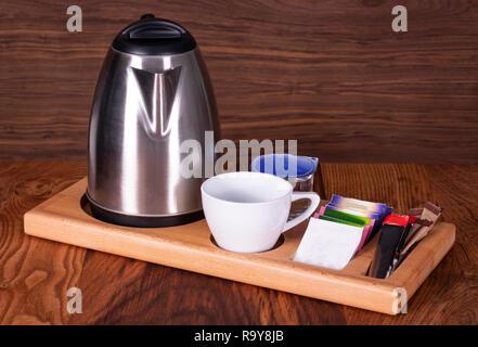 Group of coffee making set in a hotel room with stainless steel electric kettle, clean cup, teaspoon. Front view with copy space. Stock Photo