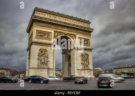 Long exposure photo of the Arc De Triomphe with ominous clouds overhead and traffic circling the roundabout, Paris, France Stock Photo