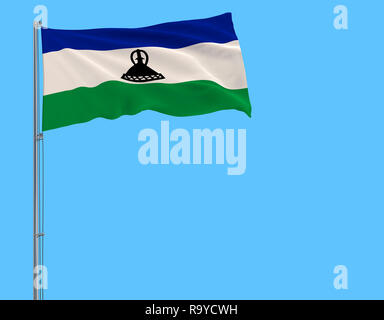 Isolate flag of Kingdom of Lesotho on a flagpole fluttering in the wind on a blue background Stock Photo