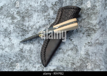 A uniquely designed fixed blade Damascus knife and leather sheath. Stock Photo