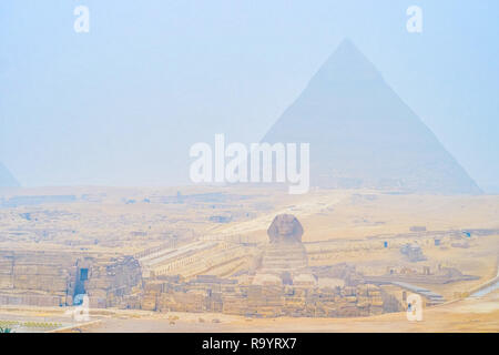 The foggy morning in Giza Necropolis with a view on Pyramid of Khafre and Great Sphinx, the wind carries the clouds of desert sand, Cairo, Egypt. Stock Photo