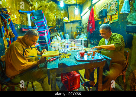 CAIRO, EGYPT - DECEMBER 20, 2017: Two carpenters in small workshop on historical El-Gamaleya street cut out the workpieces, depicting different religi Stock Photo