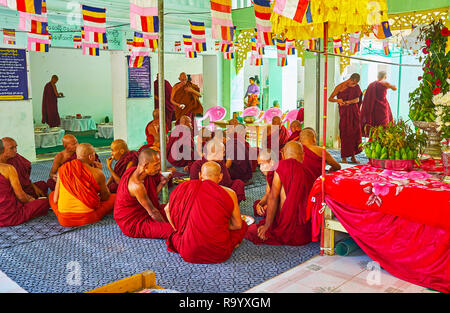 SAGAING, MYANMAR - FEBRUARY 21, 2018: The group of bhikkhu monks have a lunch in pavilion of Kaunghmudaw Pagoda, on February 21 in Sagaing. Stock Photo