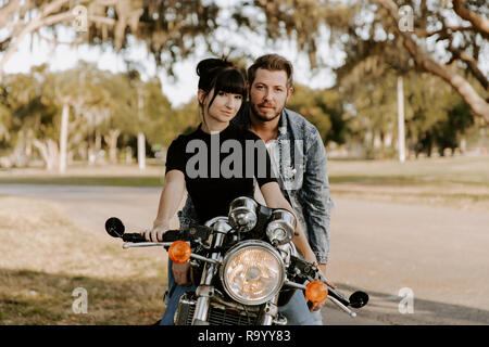 Precious Cute Leisure Lifestyle Portrait of Handsome Guy and Girl Beauty Being Silly Fun and Laughing while Riding Classic Motorcycle Bike in Love Stock Photo