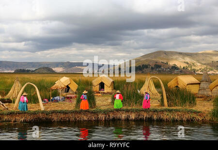 Women in traditional attires welcome tourists to visit floating Uros islands on Lake Titicaca,Peru Stock Photo