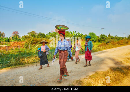 AVA, MYANMAR - FEBRUARY 21, 2018: The group of Burmese peasant women goes back after field work with food bags on their heads, on February 21 in Ava. Stock Photo