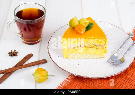 Piece of mango mousse cake on plate, white wooden table. Studio Photo Stock Photo