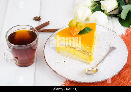 Piece of mango mousse cake on plate, white wooden table. Studio Photo Stock Photo