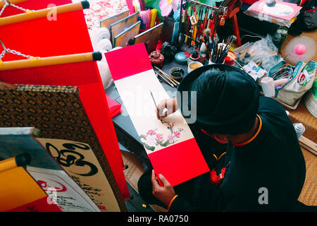Scholar writes calligraphy characters in new year. The calligrapher draw handwriting in penmanship at fair in springtime. Culture of Vietnamese Stock Photo