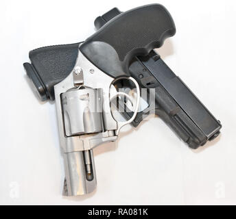 Two handguns, a silver 357 magnum revolver on top of a black 9mm pistol on a white background Stock Photo