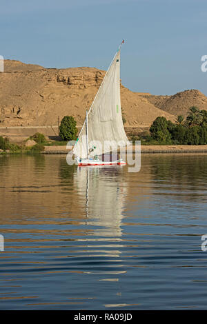 Traditional egyptian felluca sailing boat on river Nile with reflection at Aswan Stock Photo