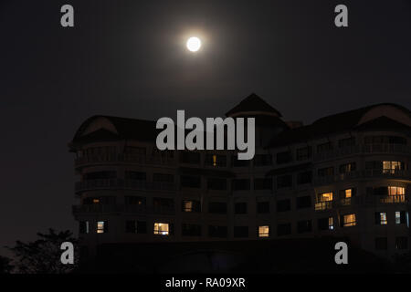 Full moon rising over building in Thailand. Stock Photo