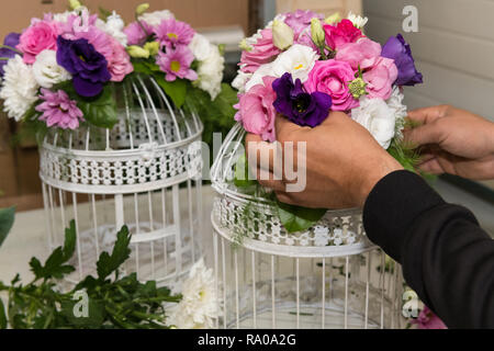 Finishing up a bridal flower display in birdcage as bloom decoration at a wedding reception. Stock Photo