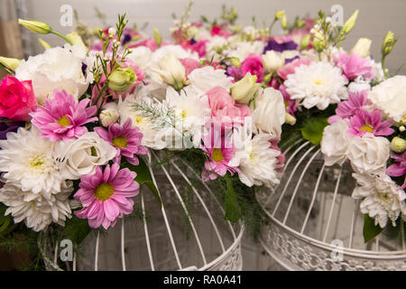 Various bridal flower heads in vintage ornate bird cage as bloom decoration at a wedding reception. Stock Photo