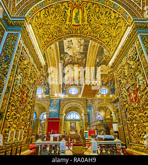 VALLETTA, MALTA - JUNE 18, 2018: The view on Grand Altar of St John's Co-Cathedral from the ornate arch of Langue of Auvergne, decorated with rich car Stock Photo