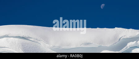 Antarctica, Antarctic peninsula, Gerlach Straight, Wilhelmina Bay in the Enterprise Island area. Moon over snowy mountain edge. Stock Photo