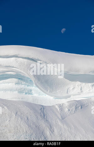 Antarctica, Antarctic peninsula, Gerlach Straight, Wilhelmina Bay in the Enterprise Island area. Moon over snowy mountain edge. Stock Photo