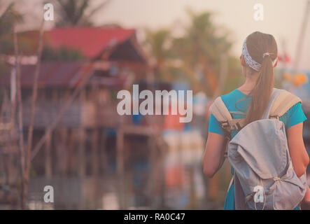 Back side of Young traveling women with backpack in fisherman village are walking in evening at asian, town. Happy female traveler and tourist concept Stock Photo