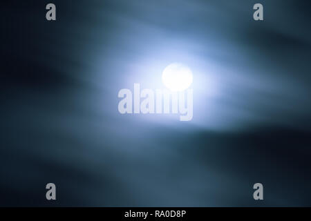 Full moon shining behind fast moving clouds; movement blur Stock Photo