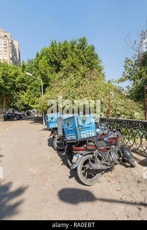 Fish Market restaurant food delivery motorbikes parked by the roadside on a sunny day in Giza, Cairo, Egypt Stock Photo