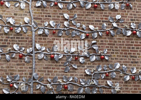 Tree of life decorated with red balls against a red brick wall Stock Photo