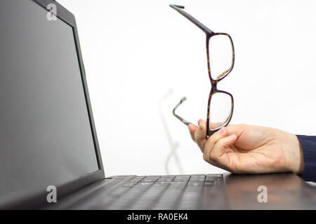 Girl holding glasses in hands leaning on the laptop while she is takingsome rest Stock Photo