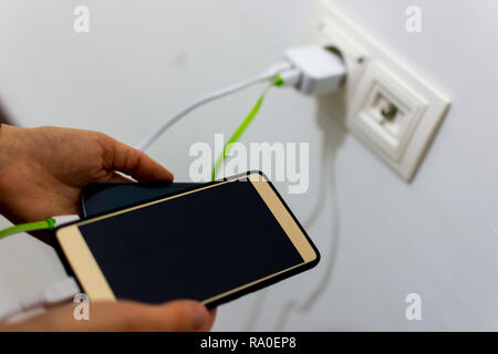 Two mobile phones charging plugged into the charger Stock Photo
