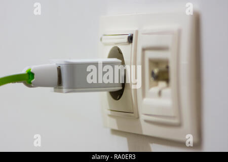 Phone charger with two connected cables pluged into the outlet Stock Photo