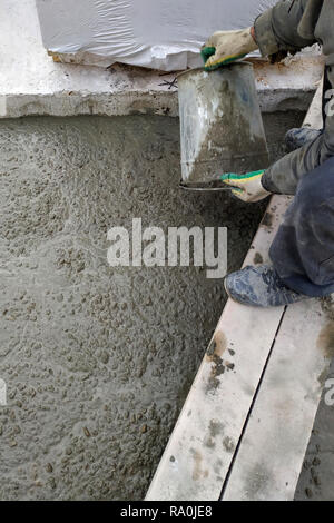 The builder pours a cement mortar slab between the floors of the house using a bucket 2018 Stock Photo