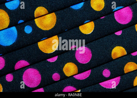Abstract background of black material with pink, blue, gold, red and green circles Stock Photo