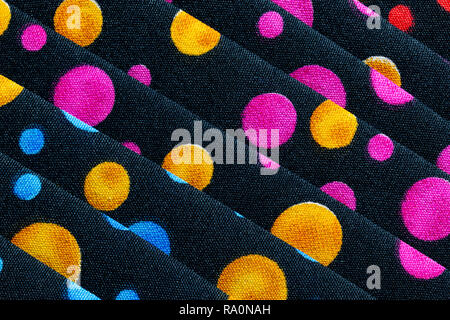 Abstract background of black material with pink, blue, gold, red and green circles Stock Photo