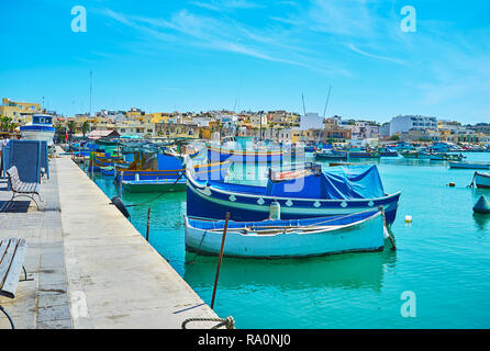 Walk along the stunning fishing harbour of Marsaxlokk, famous for traditional wooden luzzu boats, moored here, Malta. Stock Photo