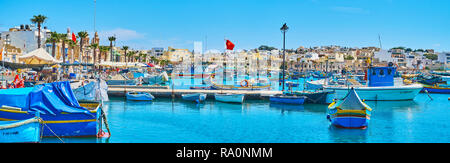 MARSAXLOKK, MALTA - JUNE 18, 2018: Panorama of resort from its harbor with a view on the traditional Maltese architecture behind the hundreds of fishi Stock Photo