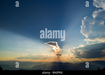 Sunset over clouds from the top, Sun rays over the mountains Stock Photo