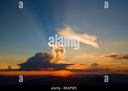 Orange sunset, sun rays breaking the clouds Stock Photo