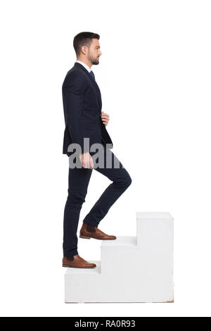 Stylish caucasian businessman walking up on steps, isolated on white,  side view Stock Photo