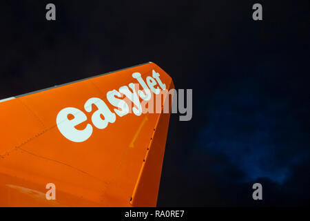 An Easyjet tailplane on the runway at night with a stormy sky above Stock Photo