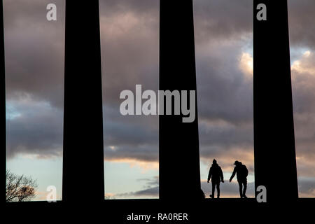 Dawn at The National Monument on Carlton Hill in Edinburgh city centre, with silhouettes of people enjoying the dramatic weather Stock Photo