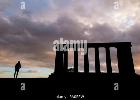 Dawn at The National Monument on Carlton Hill in Edinburgh city centre, with silhouettes of people enjoying the dramatic weather Stock Photo