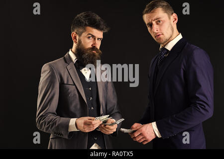 Meeting of reputable businessmen, black background. Man with beard on serious face counting money, pay to partner. Business payment concept. Businessm Stock Photo