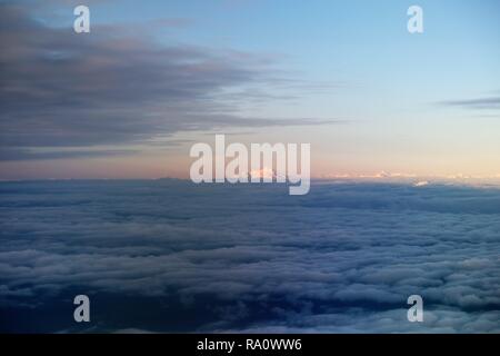 The Cascade Mountains in the Pacific Northwest (Seattle, Washington, USA); snowy mountain peak of Mount Rainier through the clouds. Stock Photo