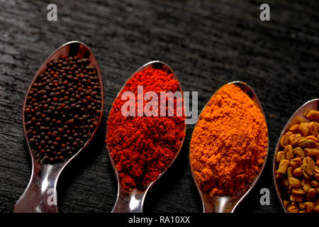 spices in spoons on black background Stock Photo